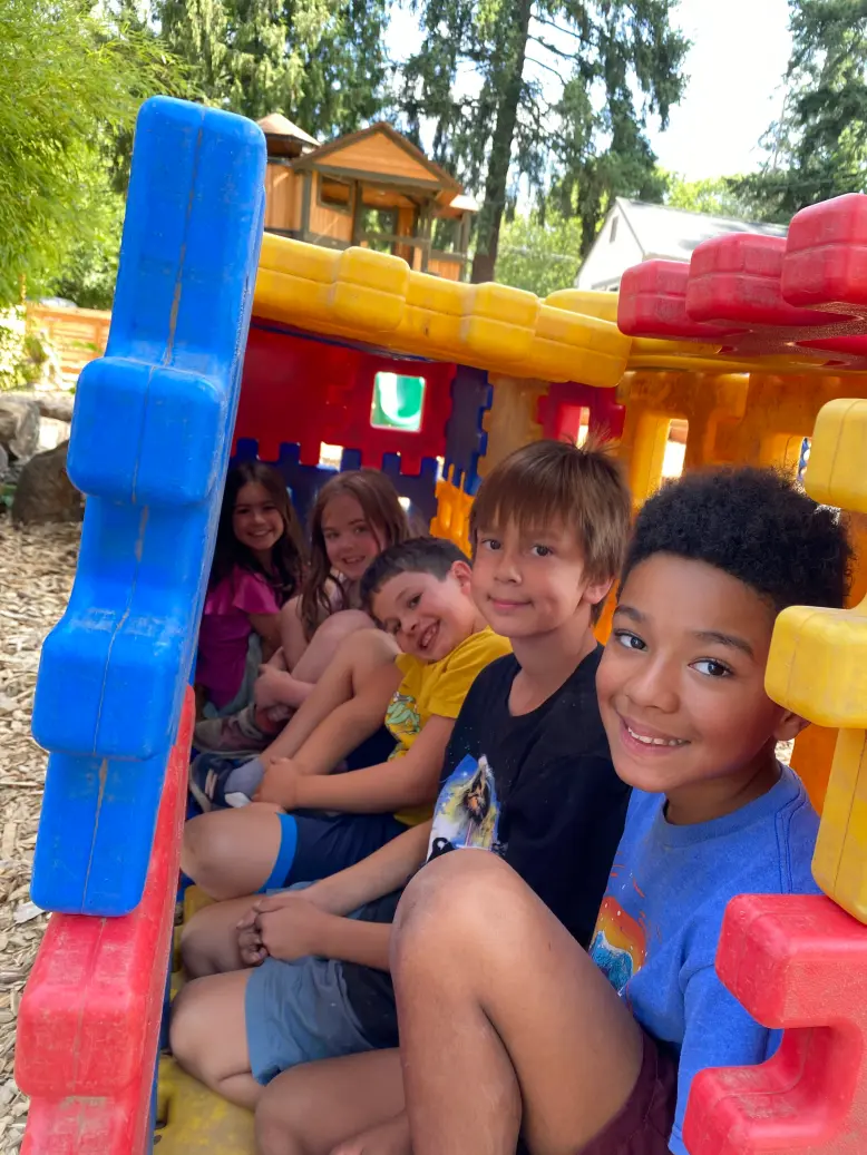 A group of campers smiling together inside a playhouse structure